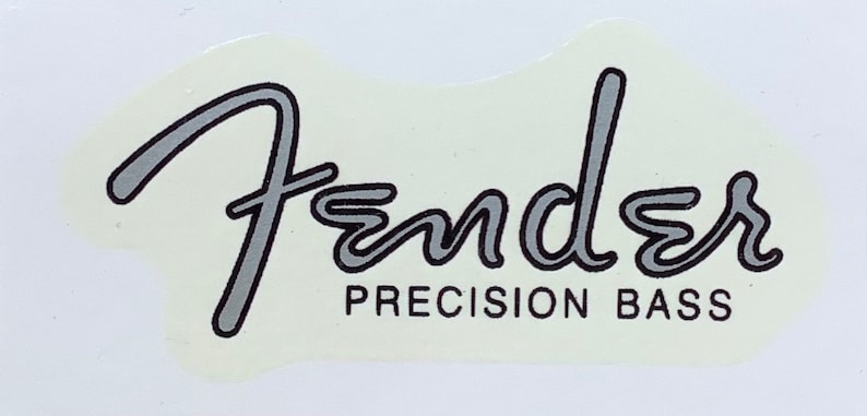 May include: A white sticker with a silver outline of the Fender logo and the text "PRECISION BASS" in black.