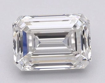 May include: A rectangular emerald-cut diamond with a clear, sparkling appearance. The facets reflect light, creating a brilliant effect. The gemstone is set against a plain, light background, highlighting its clarity and shape. This diamond is suitable for jewelry.