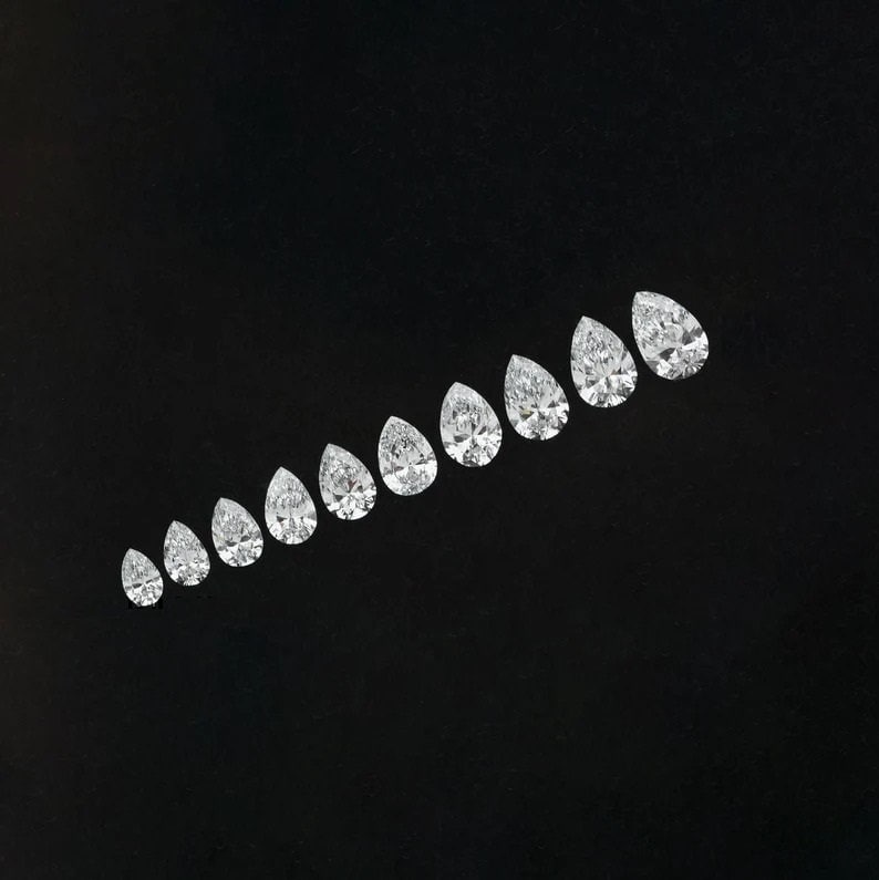 May include: A row of pear-shaped diamonds of varying sizes, arranged in a graduated pattern on a black background.