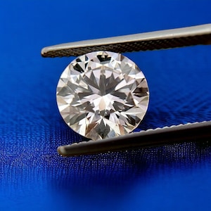May include: A large, clear, round diamond held by silver tweezers against a blue background.