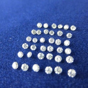 May include: A collection of small, round, clear diamonds arranged in a pattern on a blue surface.