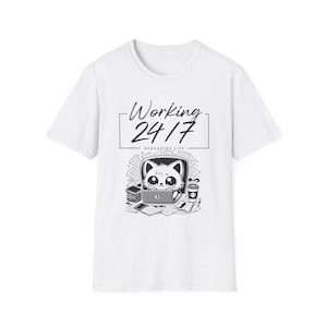 以下が含まれることがあります： ノートパソコンを使いデスクに向かう猫の黒いグラフィックがプリントされた白い半袖Tシャツ。周囲には書類やコーヒーカップが描かれ、長方形の枠内に「Working 24/7」および「DEBUGGING LIFE」というテキストが記されています。