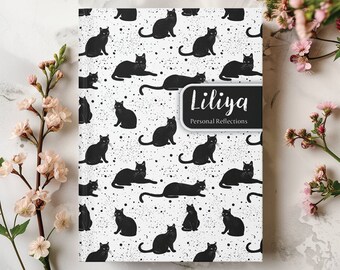 May include: A white journal with a black cat pattern and the name "Liliya" and the words "Personal Reflections" on the cover.