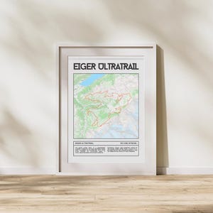 Puede incluir: Un póster enmarcado con el texto "EIGER ULTRATRAIL" en la parte superior. El póster presenta un mapa con una ruta de sendero roja, terreno verde y blanco y elementos de agua azules. La parte inferior del póster incluye texto y la distancia de 101 km / 6700 M+.