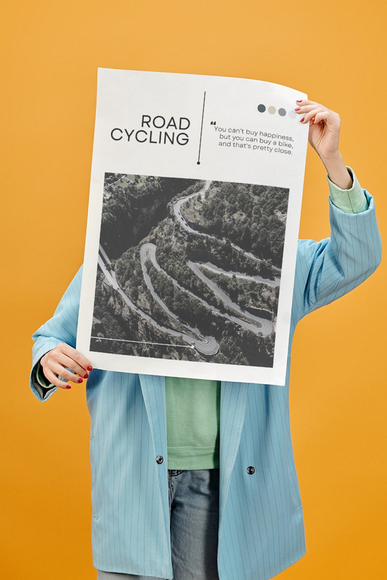 Puede incluir: Una persona sostiene un p&oacute;ster con una foto en blanco y negro de un camino sinuoso en una zona monta&ntilde;osa. El p&oacute;ster tiene el texto "ROAD CYCLING" y una cita: "No se puede comprar la felicidad, pero se puede comprar una bicicleta, y eso es bastante cerca."
