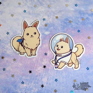 May include: Two cartoon stickers of a dog wearing a space suit and a dog wearing a blue and white backpack. The stickers are on a purple and blue background with white stars.