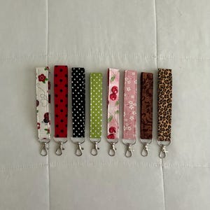 May include: A white ceramic mug with a black handle and the text "But First, Coffee" in a bold, black font. The mug is set against a blurred background, suggesting a cozy setting.