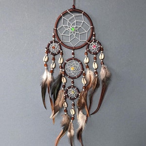 May include: A brown dream catcher with white netting and colorful beads. It has four hoops with feathers and shells hanging from the bottom.
