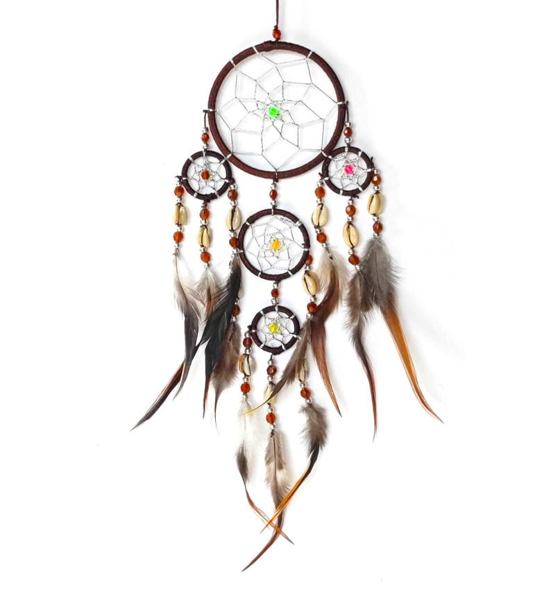 May include: A brown dreamcatcher with feathers and beads. The dreamcatcher has four circles, with the largest circle at the top and the smallest circle at the bottom. The dreamcatcher is decorated with brown beads and feathers.