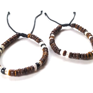 May include: Two brown and white beaded bracelets with black string ties.