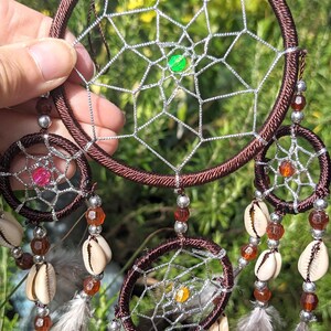 May include: A brown dream catcher with multiple layers of netting and beads. The dream catcher has a variety of shells and feathers hanging from it.