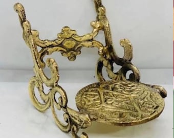 Peut inclure: Un support décoratif en métal doré avec un dessus rond et un motif de volutes ornées. Le support a un design délicat et complexe.