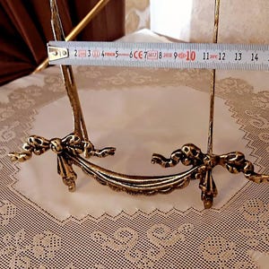 Peut inclure: Un chevalet &agrave; photo en m&eacute;tal dor&eacute; avec un motif de ruban d&eacute;coratif. Le chevalet mesure 25,4 cm de haut.