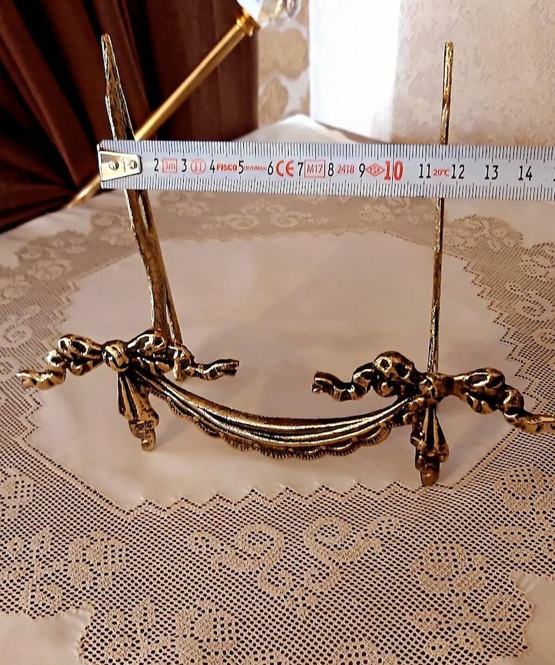 Peut inclure: Un chevalet &agrave; photo en m&eacute;tal dor&eacute; avec un motif de ruban d&eacute;coratif. Le chevalet mesure 25,4 cm de haut.