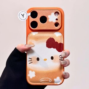 May include: Orange phone case with a Hello Kitty design. The case has a textured orange border and a white and orange background with a Hello Kitty face and a red bow. The text "Hello Kitty" is at the bottom.