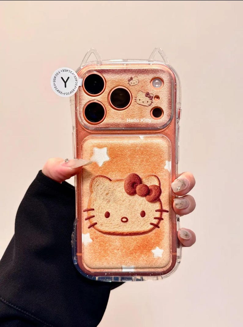 May include: A clear phone case featuring a Hello Kitty design. The case has a brown background with a Hello Kitty face and stars. The top of the case has a Hello Kitty design and the words "Hello Kitty".