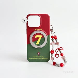 May include: A red and green phone case featuring the name Ronaldo, the number 7 in yellow, and the text No dream is too big when you dare to outwork everyone. A beaded wrist strap with red, silver, and clear beads and a small red bow charm is attached.