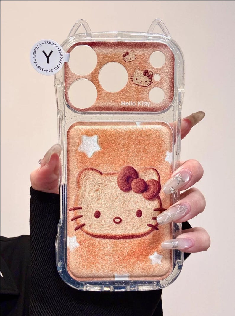 May include: Clear phone case with a Hello Kitty design. The case features a light brown background with a Hello Kitty face and stars. The top section has a brown background with Hello Kitty and the words "Hello Kitty".