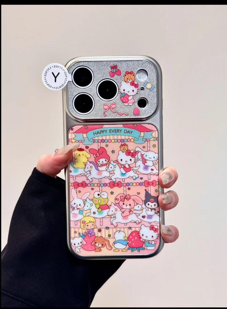 K&ouml;nnte beinhalten: Handyh&uuml;lle mit silbernem Kamerabereich und rosa-wei&szlig;em Karussell-Design. Die H&uuml;lle zeigt Zeichentrickfiguren und den Text "HAPPY EVERY DAY".