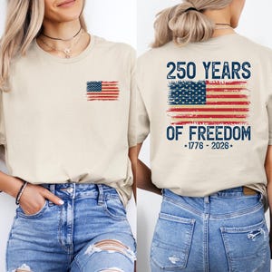 A woman wearing a beige t-shirt with an American flag design and text printed on the back.