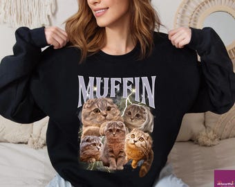 May include: Black sweatshirt featuring a graphic of five Scottish Fold cats with the word "MUFFIN" in white block letters. The cats are in various poses, with a lightning bolt design behind them. The sweatshirt is a crew neck style.