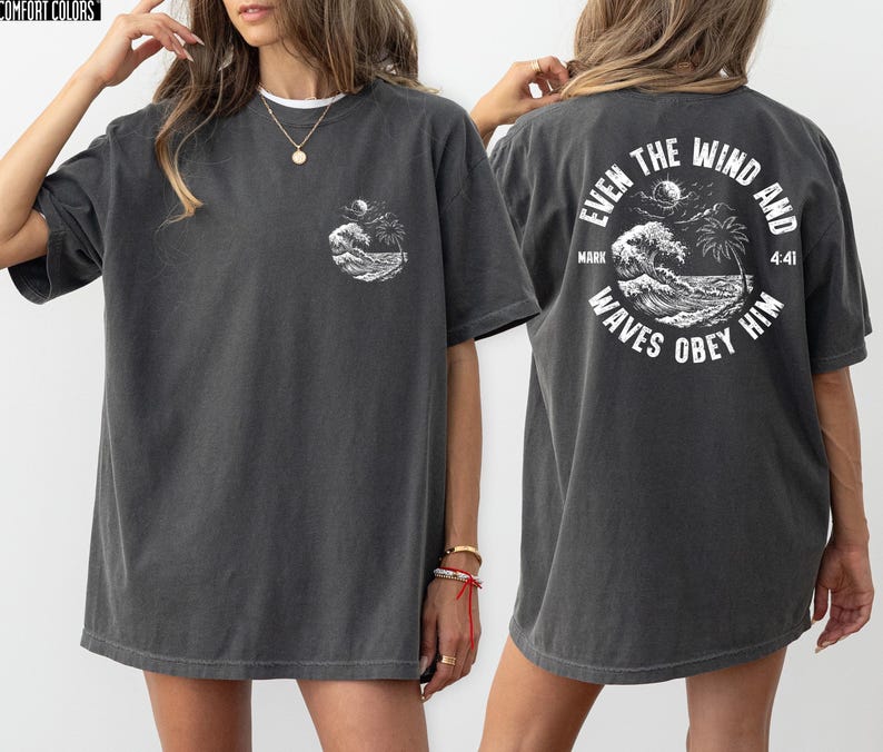"Back view of a Pepper Grey Comfort Colors oversized shirt with a vintage nautical Christian design. High-contrast white ink printing showing ocean scenery and scripture Mark 4:41."