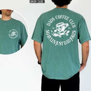 A man wearing a green t-shirt with a graphic design and text on the back.