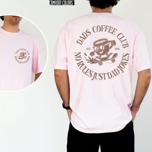A man wearing a pink t-shirt with a graphic design on the back.