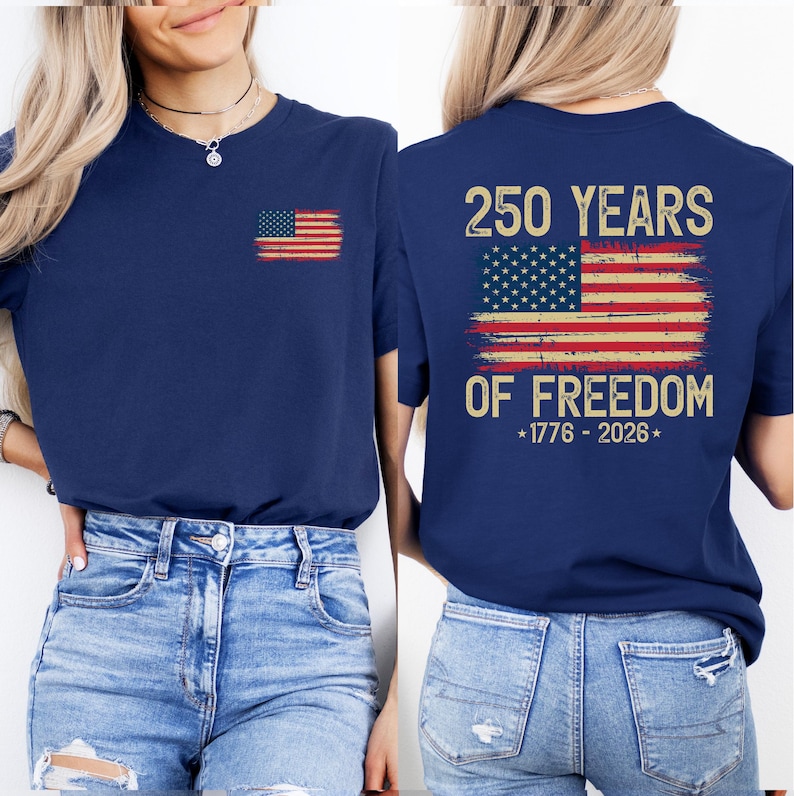 A woman wearing a navy blue t-shirt with a graphic design of the American flag and the text "250 YEARS OF FREEDOM" printed on the back.