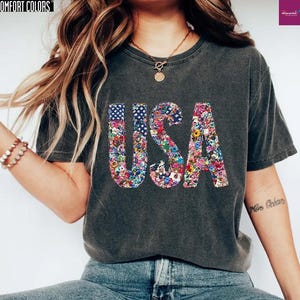 a woman wearing a usa t - shirt and jeans
