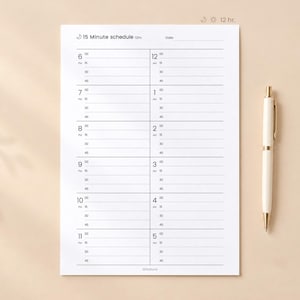 May include: A white paper 15 minute schedule planner sheet with black text and lines, featuring hourly slots from 6 to 5, alongside a cream-coloured ballpoint pen with gold accents. The header includes the text 15 Minute schedule 12hr.