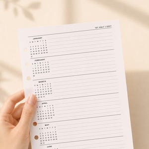 May include: A white planner refill page featuring a 2027 calendar for the first half of the year. The page includes monthly grids for January through June, each accompanied by horizontal lines for notes, and has three circular binder holes.