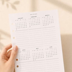 May include: A white paper planner insert for the first half of 2027, featuring six monthly calendar grids from January to June. The page includes black text, horizontal lines for notes under each month, and five circular binder holes on the left side.