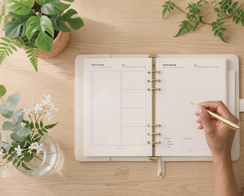 Pode incluir: Uma agenda de argolas aberta com p&aacute;ginas cor de creme com cabe&ccedil;alhos Brain Dump, um layout de grade de pontos e caixas de sele&ccedil;&atilde;o de prioridade. A agenda tem uma capa clara com argolas douradas e uma caneta dourada na p&aacute;gina direita.