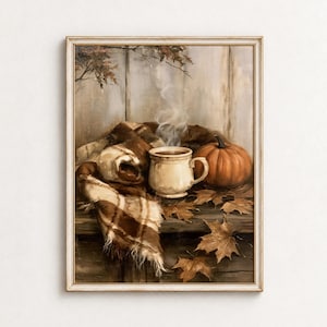 May include: A framed oil painting depicting a steaming ceramic mug, a vibrant orange pumpkin, and a brown plaid blanket resting on a wooden surface. Scattered dried maple leaves surround the objects against a rustic, light-colored wooden wall.