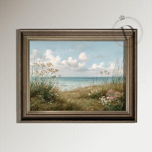 K&ouml;nnte beinhalten: Gerahmtes Landschaftsgem&auml;lde, das eine K&uuml;stenlandschaft mit blauem Himmel und wei&szlig;en Wolken zeigt. Der Vordergrund zeigt hohe Gr&auml;ser und Wildblumen in Gr&uuml;n, Gelb und Rosa. Der Rahmen ist ein dunkles, verwittertes Braun.