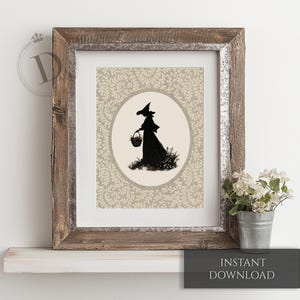 May include: Framed print featuring a black silhouette of a witch carrying a basket, set against a beige floral pattern. The artwork is enclosed in a rustic, weathered wooden frame. The words "INSTANT DOWNLOAD" are at the bottom.