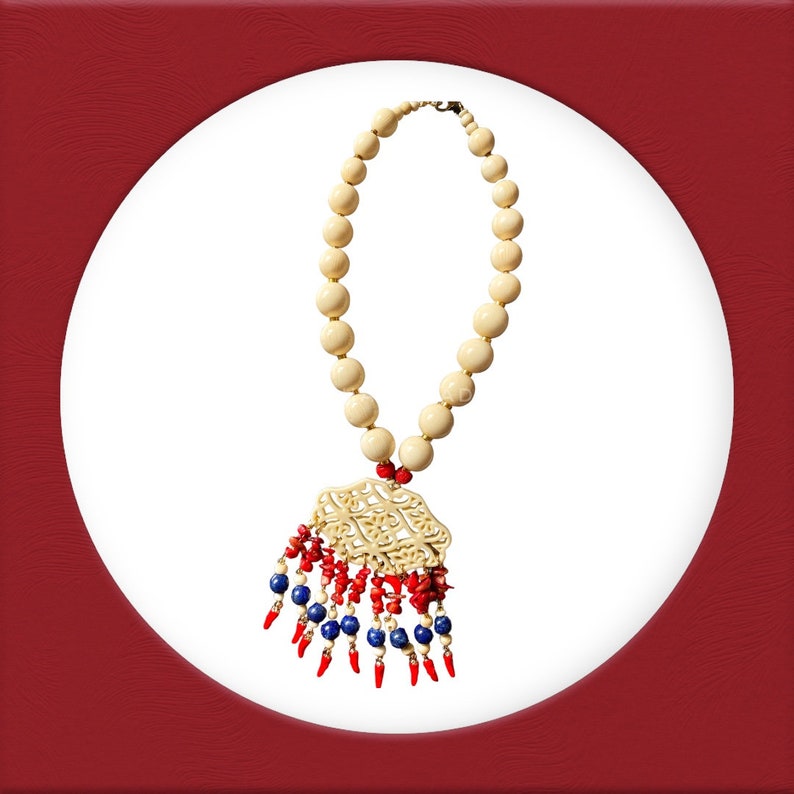 May include: A white bead necklace with a carved ivory pendant and red and blue bead fringe.