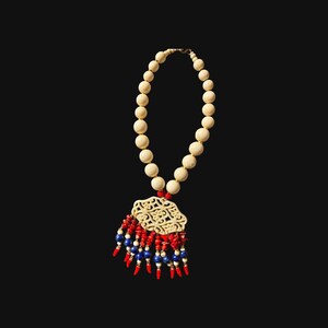 May include: A white beaded necklace with a carved ivory pendant and red and blue bead accents.