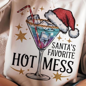Puede incluir: Una sudadera blanca con un diseño de cóctel festivo. El gráfico incluye una copa de martini con cubitos de hielo, un gorro de Papá Noel y el texto "Santa's Favorite Hot Mess". Estrellas doradas completan el tema navideño.