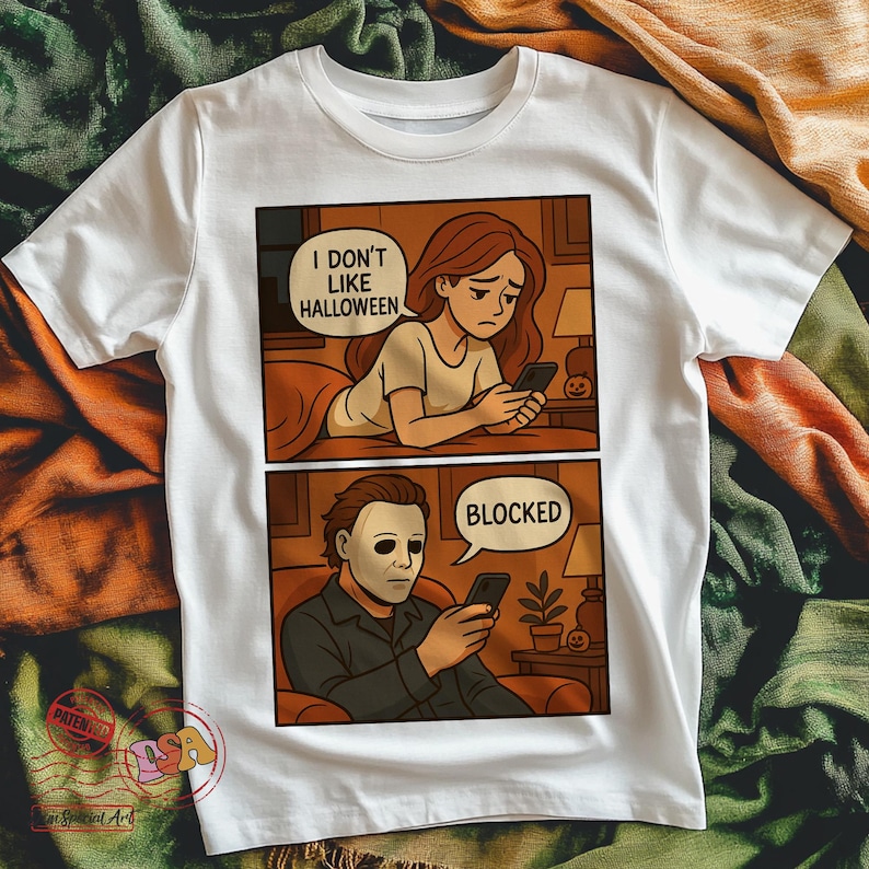 K&ouml;nnte beinhalten: Wei&szlig;es T-Shirt mit einem zweiteiligen Comic. Das obere Panel zeigt eine Frau, die textet, mit dem Text "I DON'T LIKE HALLOWEEN". Das untere Panel zeigt eine Person mit Maske, die textet, mit dem Text "BLOCKED".