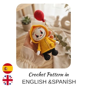 May include: A small crocheted doll featuring a white face with red and black facial details, wearing a yellow hooded raincoat and black pants. The doll holds a thin string attached to a round, textured red balloon. The text reads Crochet Pattern in ENGLISH & SPANISH.