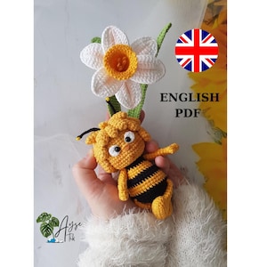 May include: A crocheted bee toy with black and yellow stripes, and a daffodil flower. The flower has white petals and a yellow centre. The text "ENGLISH PDF" is visible.