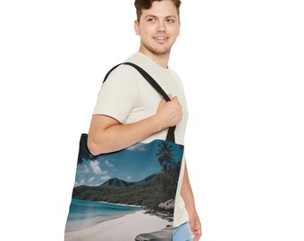 May include: A person is carrying a black tote bag with a beach scene printed on it. The scene features a white sandy beach, turquoise water, and palm trees.