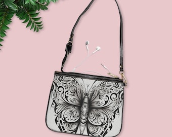 May include: Black leather crossbody bag with a white and black butterfly design. The bag has a zipper closure and a long adjustable strap.