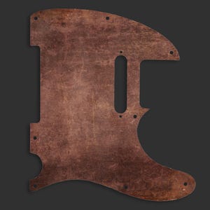 May include: A brown guitar pickguard with a distressed, textured finish. The pickguard has a distinctive shape, featuring a long, vertical pickup slot and several screw holes. The design evokes a vintage or rustic aesthetic.