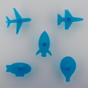 May include: Five light blue plastic cookie cutters shaped like a plane, rocket, blimp, hot air balloon, and jet. Each cutter has a small circular detail in the centre.