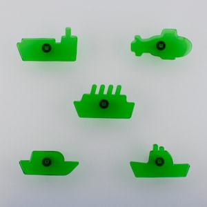 May include: Five translucent green cabinet knobs in the shape of transport vehicles. The knobs depict a ship, a cruise ship, a boat, a helicopter, and a tugboat. Each knob has a black central screw for fixing.