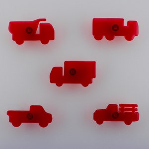 May include: Five red toy trucks in different styles, such as a dumper truck and a lorry. Each truck features a small, circular detail in the middle. The trucks are set against a white backdrop.