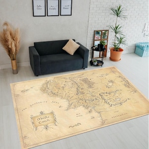 Könnte beinhalten: Ein rechteckiger beigefarbener Teppich mit einer detaillierten Karte von Mittelerde. Die Karte enthält geografische Merkmale, Text und einen dekorativen Rahmen mit den Worten "Middle Earth". Der Teppich liegt auf einem hellen Boden.